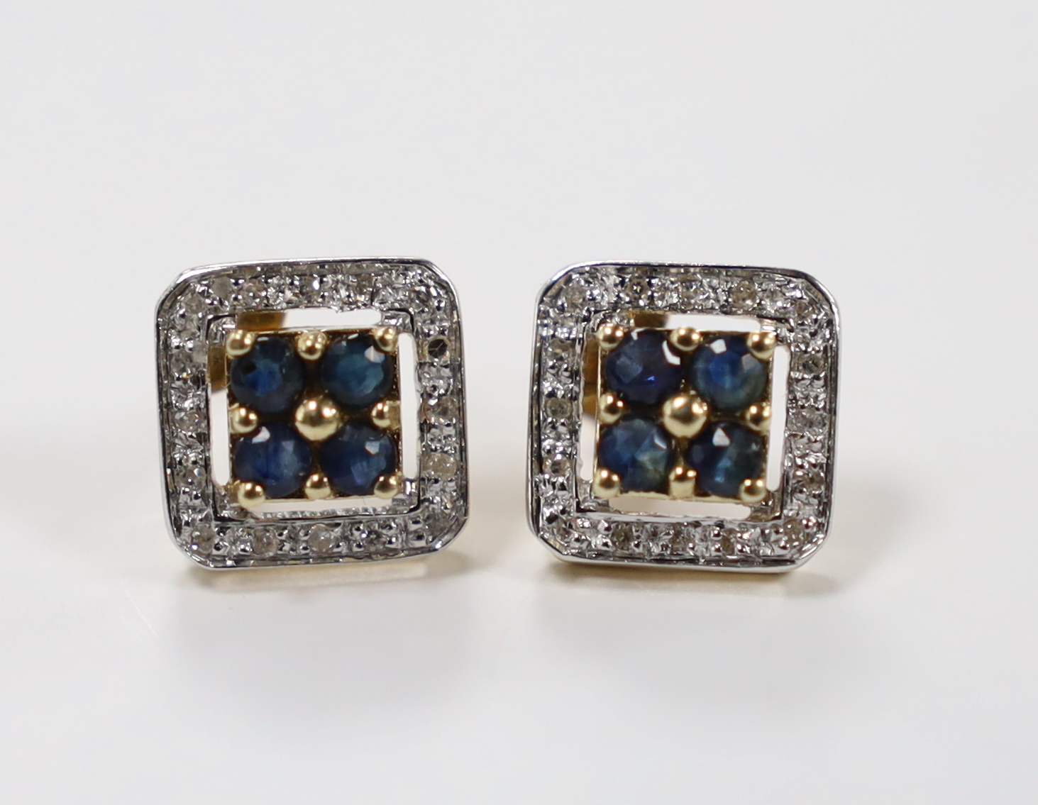 A modern pair of 375 yellow metal, sapphire and diamond chip set square cluster earrings, one butterfly missing, 10mm, gross weight 2.4 grams.